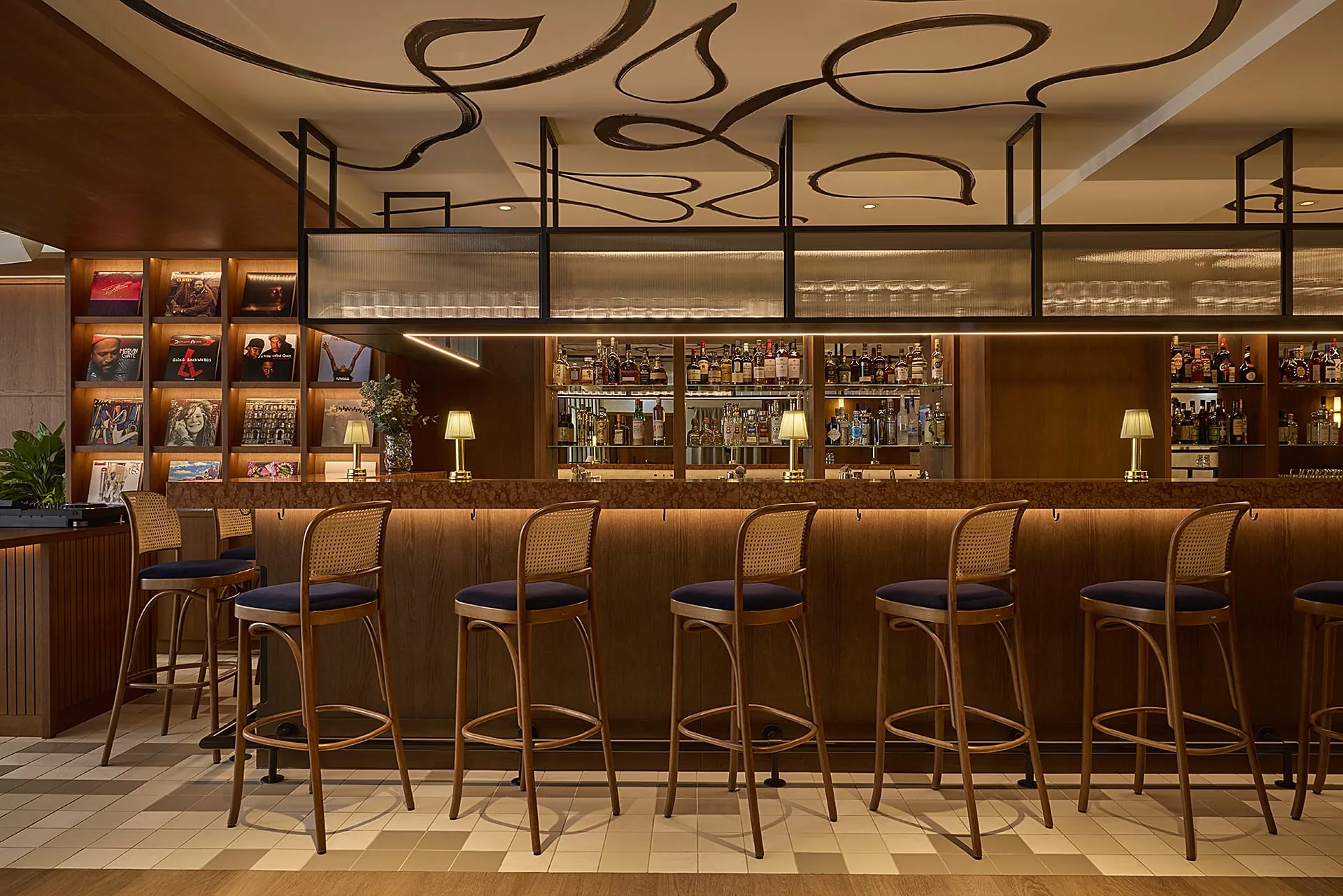 An der langen Theke mit Steinauflage reihen sich Bugholz-Barhocker mit Wiener Geflecht und dunkelblauen Sitzpolstern.