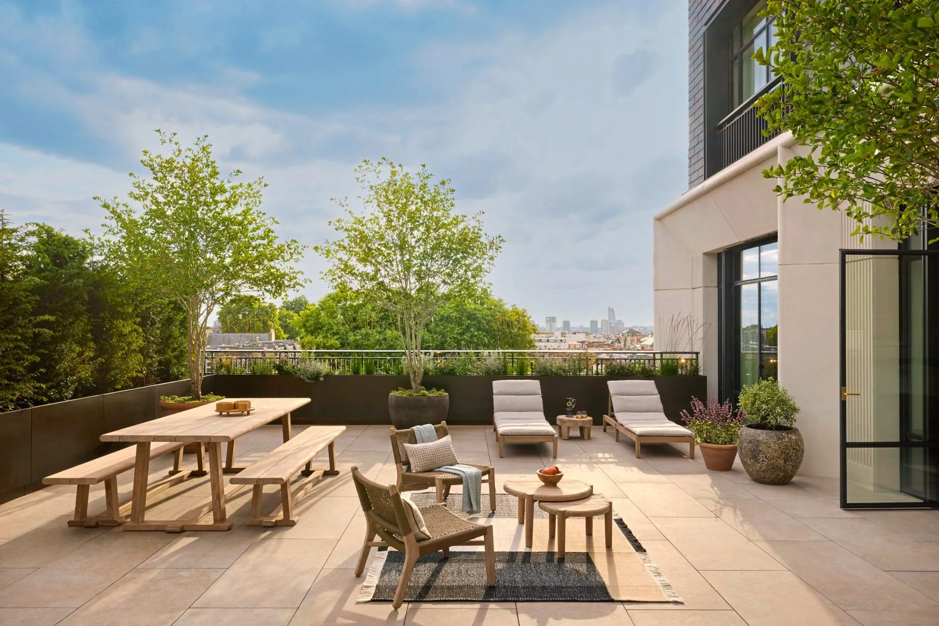 Die großzügige Dachterrasse der Notting Hill Suite bietet Sonnenliegen, einen Holztisch mit Bänken und Blick über die Londoner Skyline.