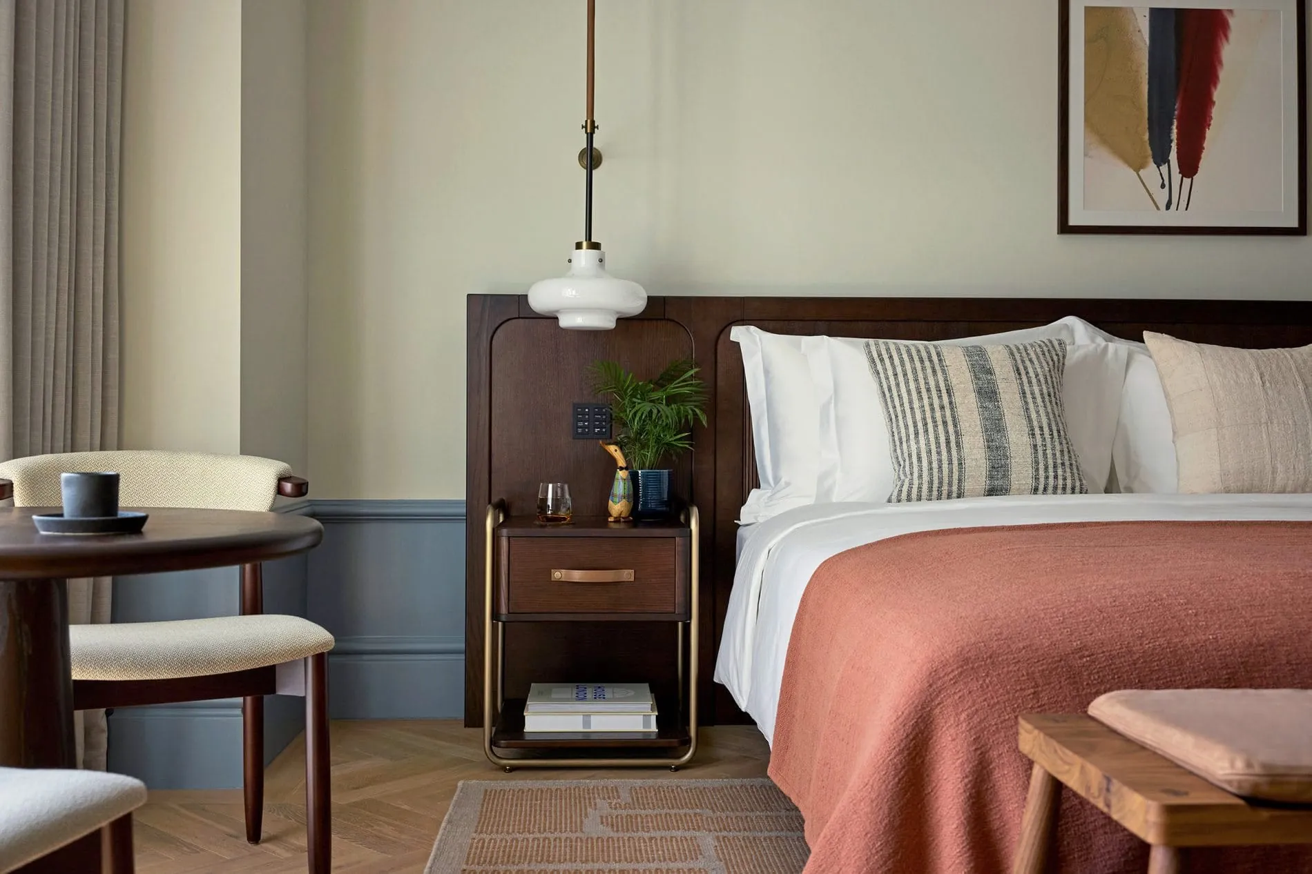 Ein Dunkles Holzkopfteil, eine lachsfarbene Tagesdecke und handwerkliche Details wie ein Messingrahmen-Nachttisch prägen das Design der Premier Rooms.