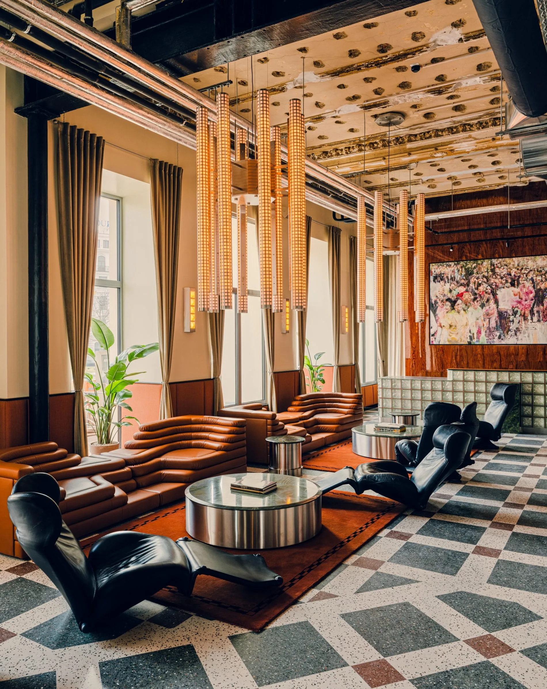 Cognacfarbene Ledersofas, schwarze Designersessel und zylindrische Pendelleuchten prägen die Lobby des The Companion Vienna.