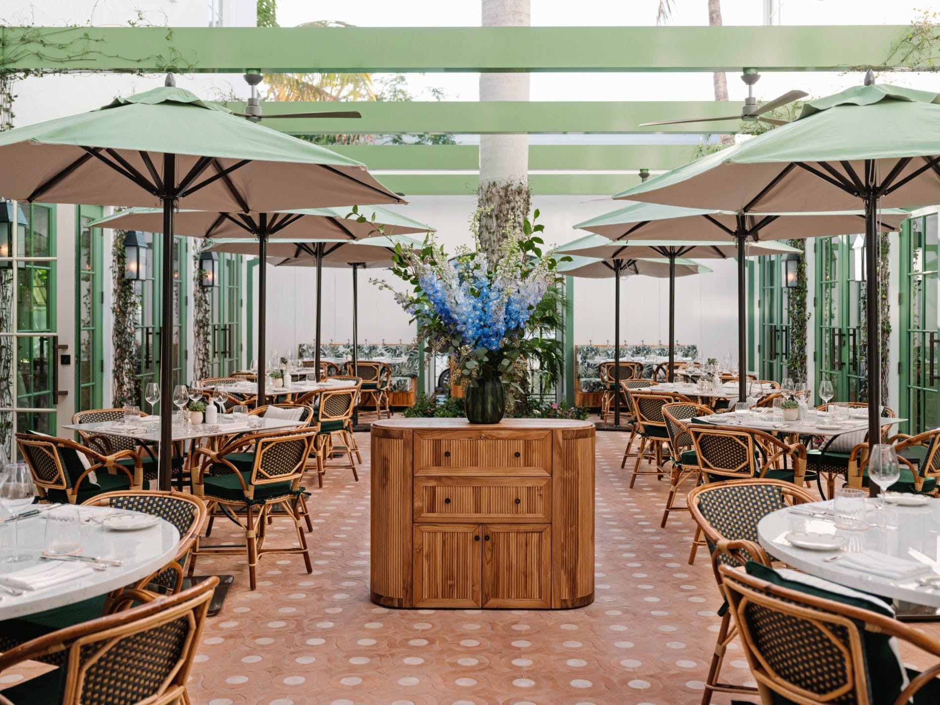Im mit Jasmin bepflanzten Innenhof des Restaurants Coco's speisen Gäste unter freiem Himmel zwischen Rattanstühlen, mintgrünen Sonnenschirmen und üppigen Blumenarrangements.