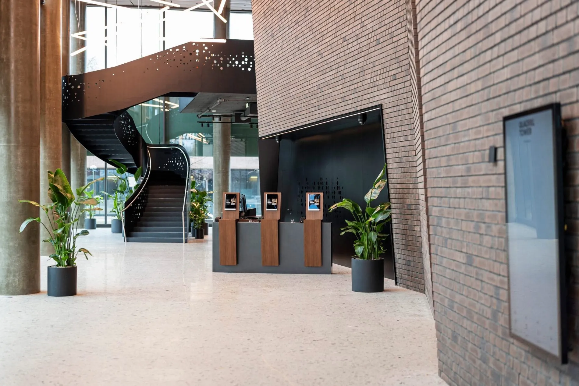 Die geschwungene Wendeltreppe mit perforiertem Metallgeländer verbindet die Lobby mit den oberen Etagen und setzt einen architektonischen Akzent.