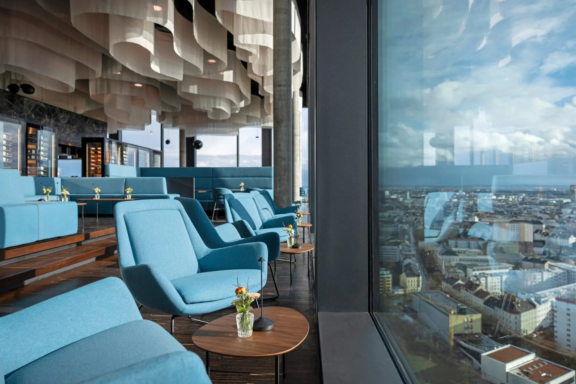 Skulpturale Deckenelemente, beleuchtete Weinvitrinen und blaue Lounge-Möbel schaffen im Q27 eine entspannte Atmosphäre.