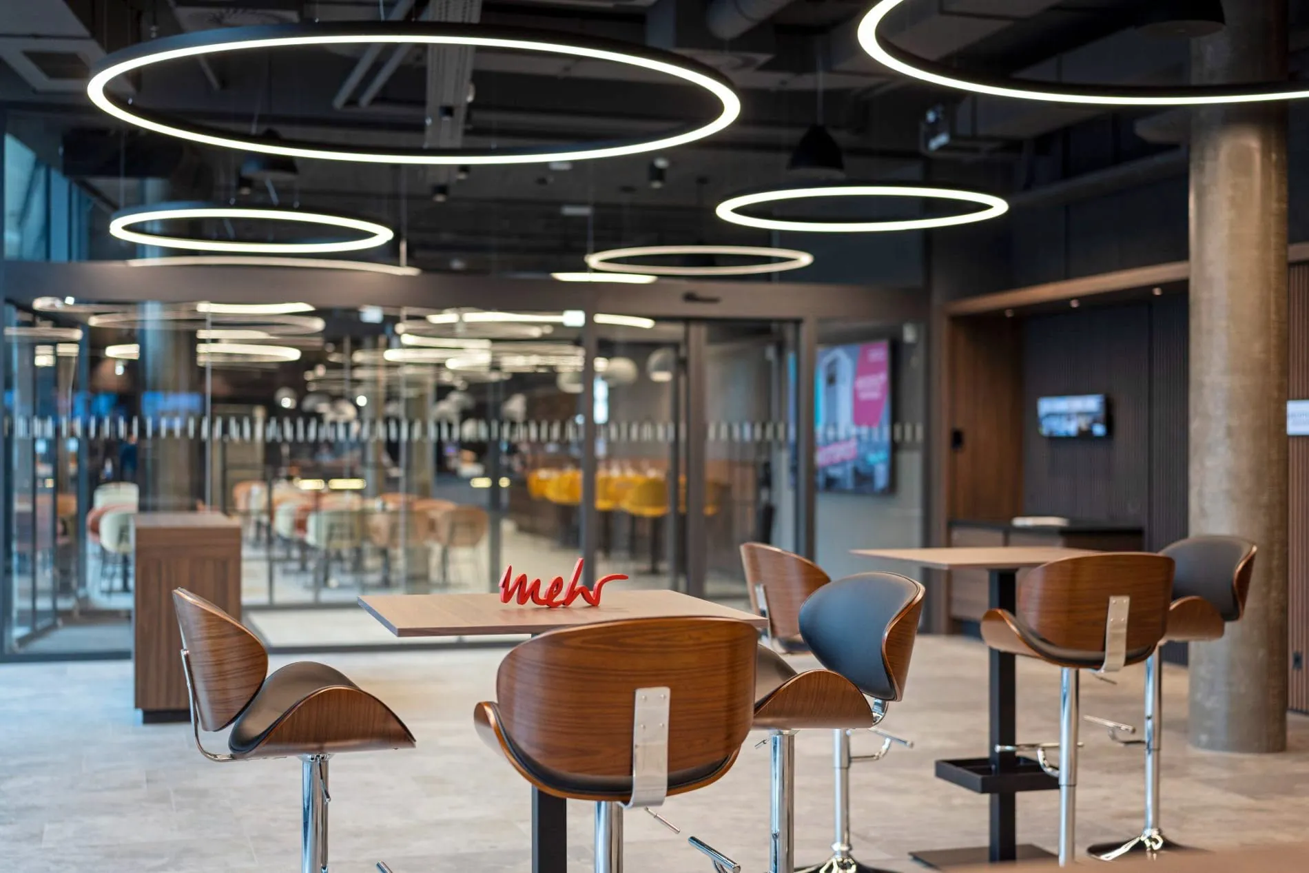 Stehtische mit Designbarhockern und ringförmige LED-Leuchten erwarten Konferenzgäste in den Seminarräumen.