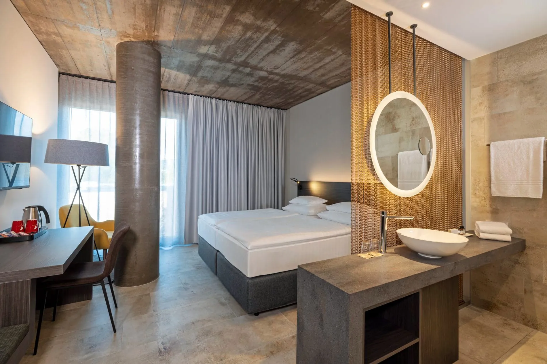 Offene Raumgestaltung verbindet Schlaf- und Badbereich: Ein Metallkettenvorhang trennt das Waschbecken dezent vom Bett ab.