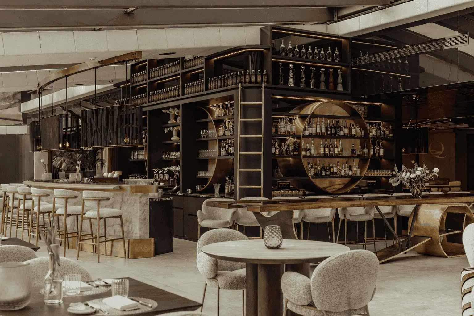 Die Hotelbar ist das architektonische Herzstück des Quellenhof Luxury Resort Passeier bei Meran. Schwarz-, Beige- und Goldtöne setzen Akzente und verleihen dem Design eine zeitlose Ästhetik.