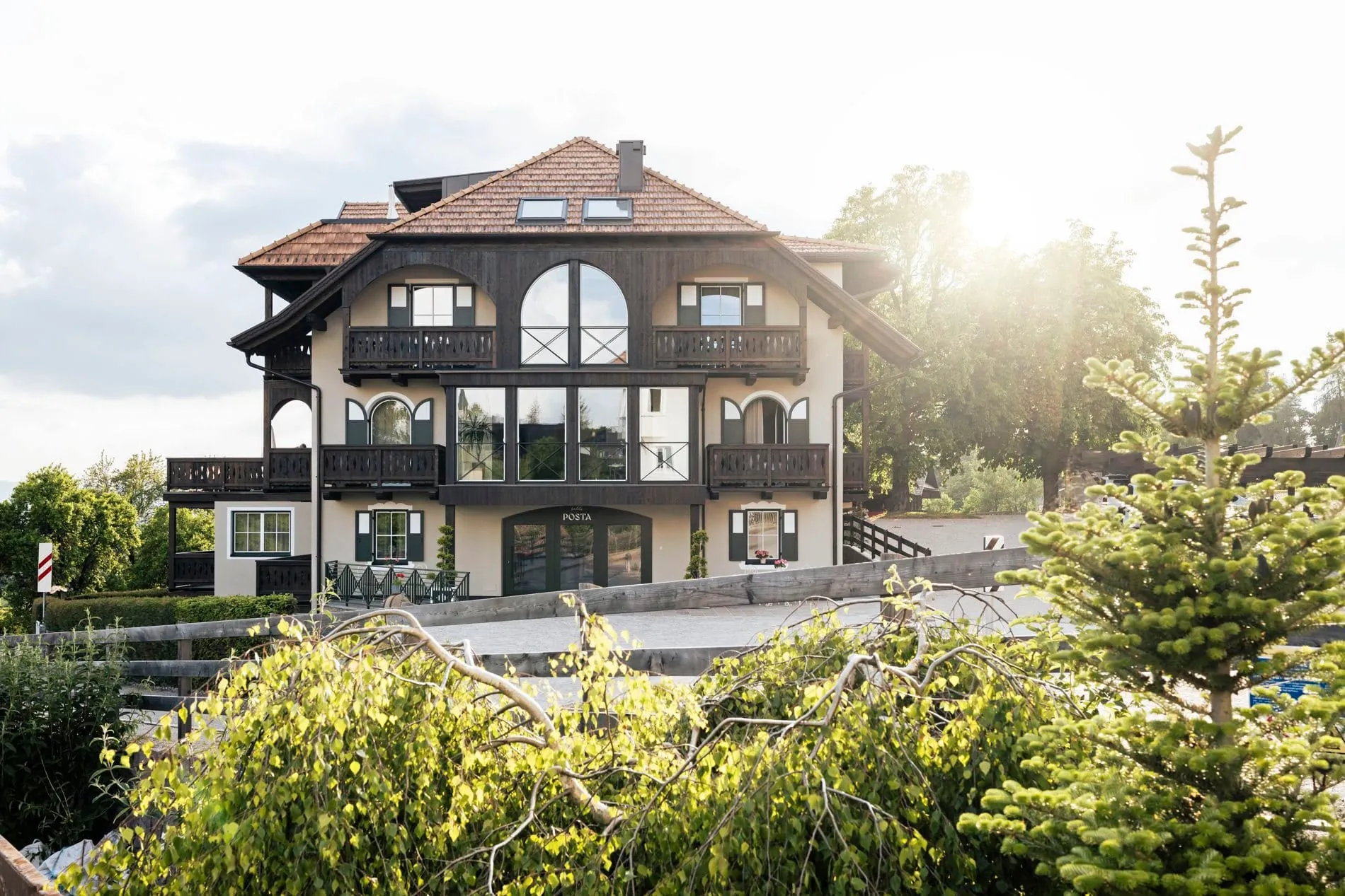 Eine markante Fassade mit dunklem Holz, Rundbogenfenstern und traditionellen Balkonen prägt das Bella Posta in Oberbozen, das sich als lässiger Gegenentwurf zum klassischen Berghotel versteht.