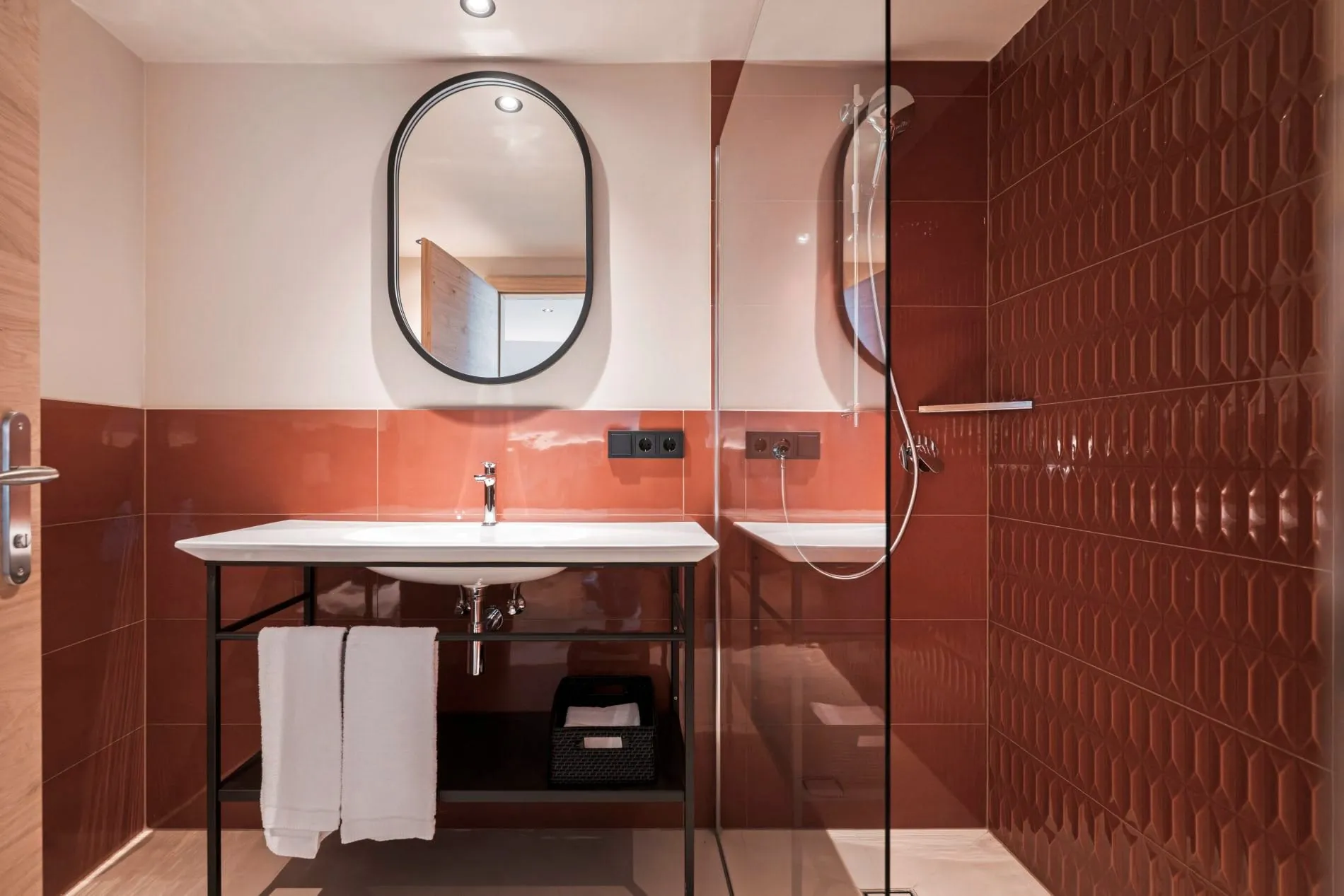 länzende Terrakotta-Fliesen und ein schwarzer Stahlrahmen-Waschtisch prägen das Bad der Junior Suite.