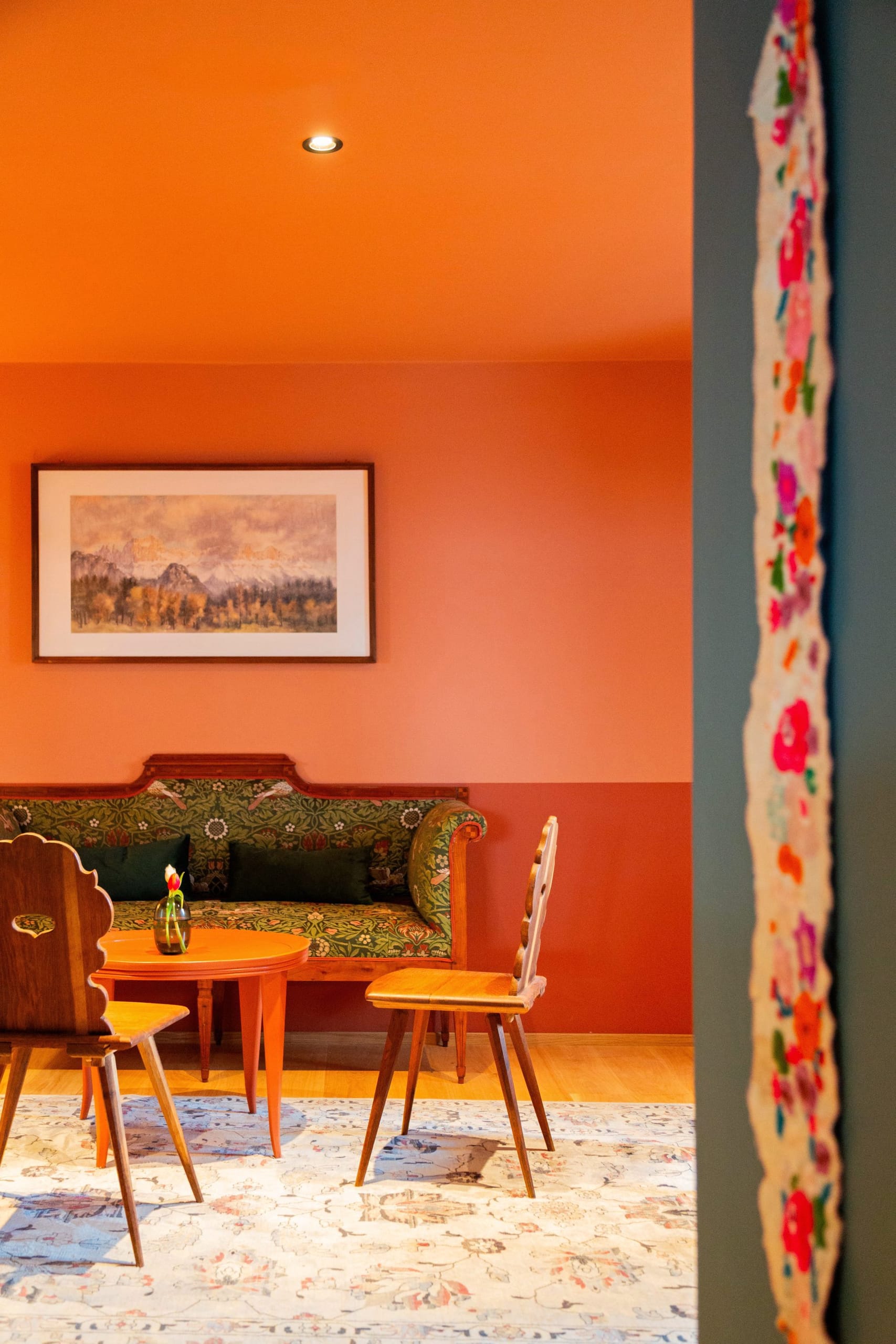 Kräftige Orangetöne, ein floral bezogenes Biedermeier-Sofa und handgeschnitzte Stühle verleihen dem Eingangsbereich den fröhlichen Retro-Charakter, den die Familie Holzner für das Bella Posta gewählt hat.
