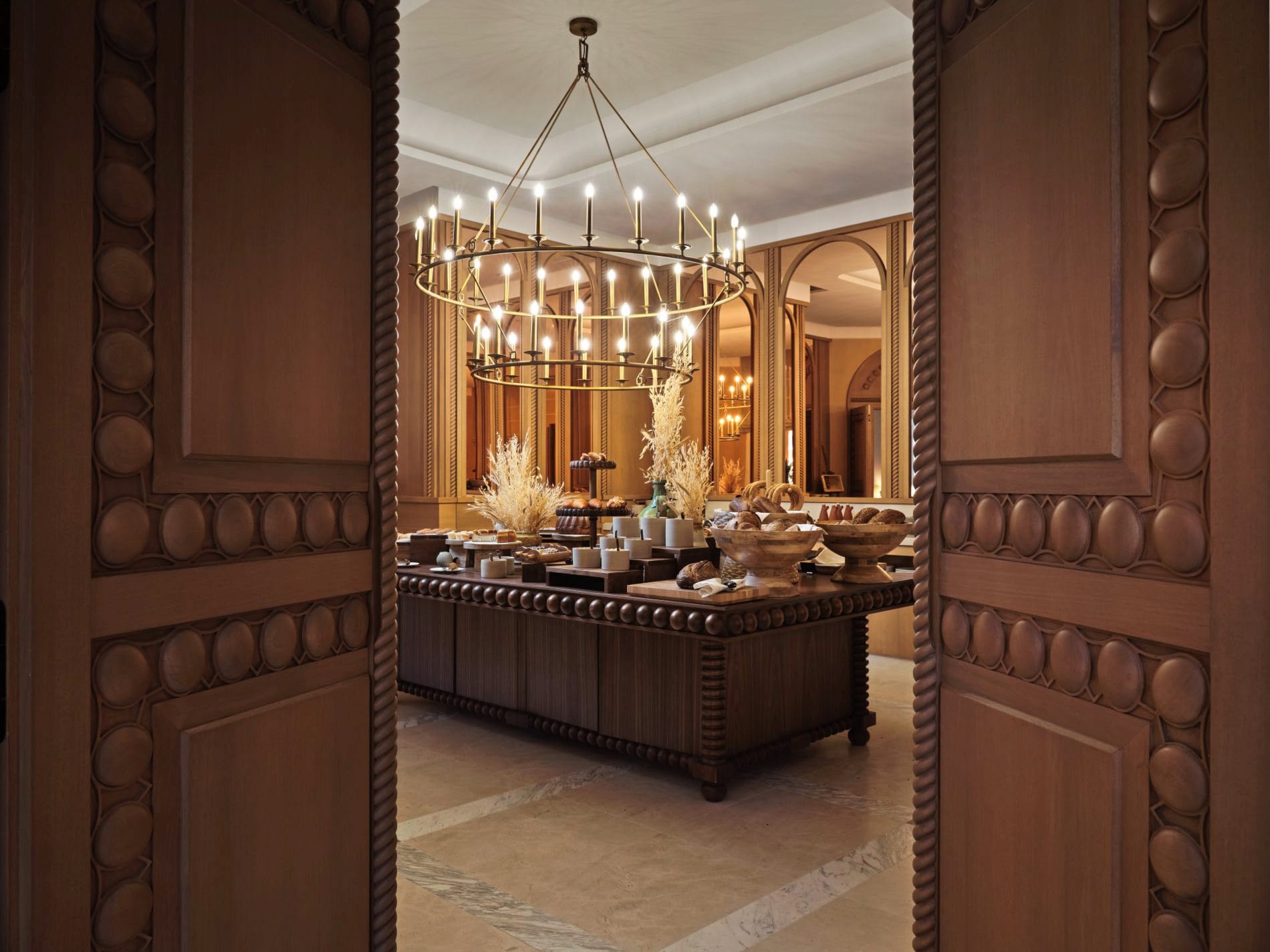 Das Frühstücksbuffet des Byzantino wird von einem geschmiedeten Kerzenleuchter und kunstvoll geschnitzten Holztüren gerahmt.