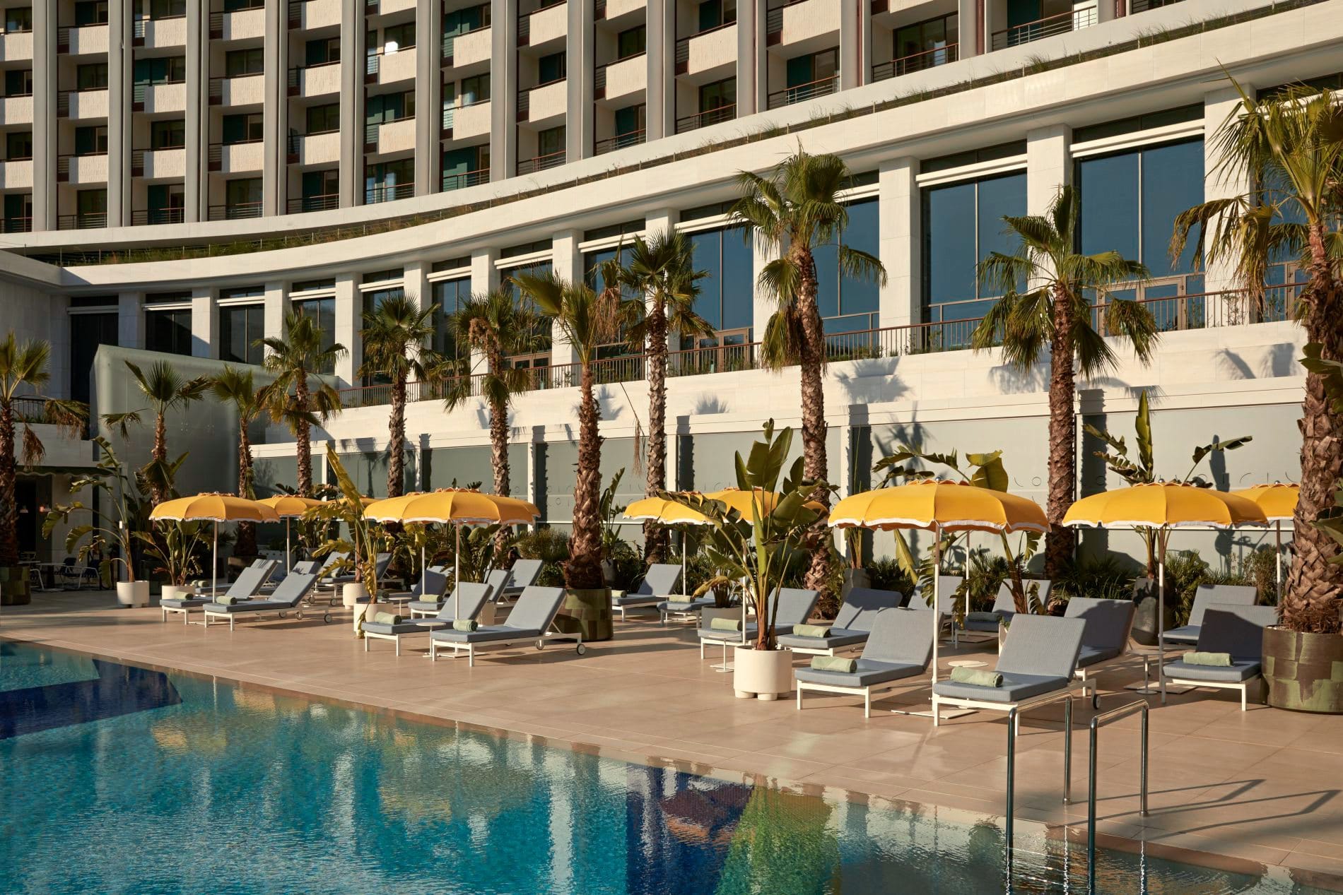 Die „Oasis“ gilt als größter Außenpool Athens. Palmen, gelbe Sonnenschirme und Liegen schaffen mediterranes Resortflair mitten in der Stadt.