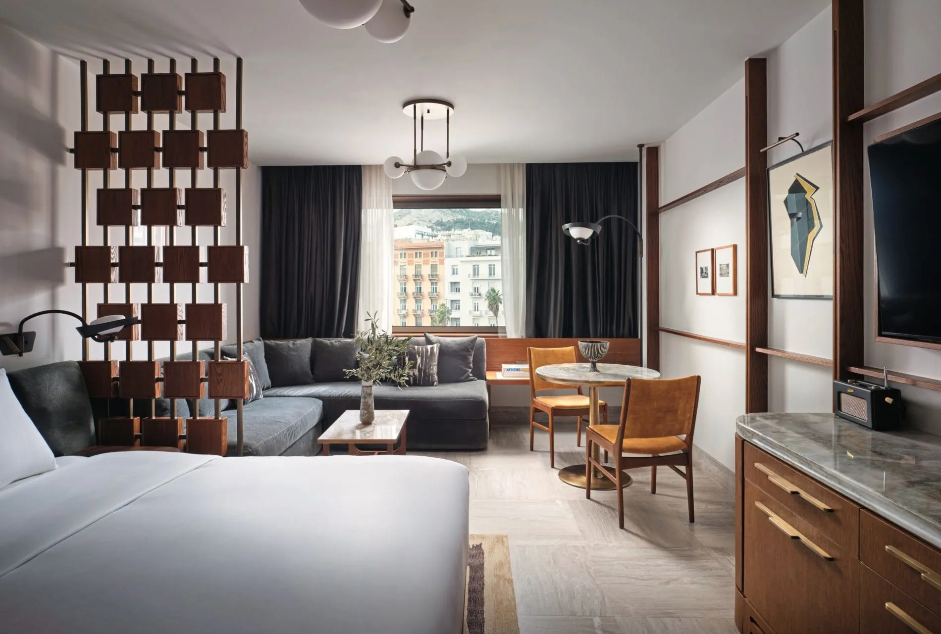Mid-Century-Elemente wie ein hölzerner Raumteiler und Vintage-Radio verweisen in den Zimmern auf die Hotelgeschichte ab 1963.