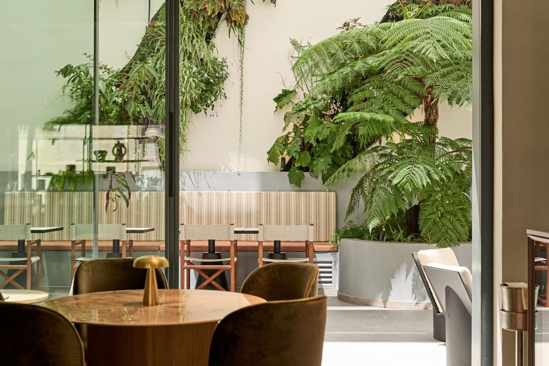 Großflächige Glasflächen verbinden die Lounge mit dem üppig bepflanzten Innenhof.