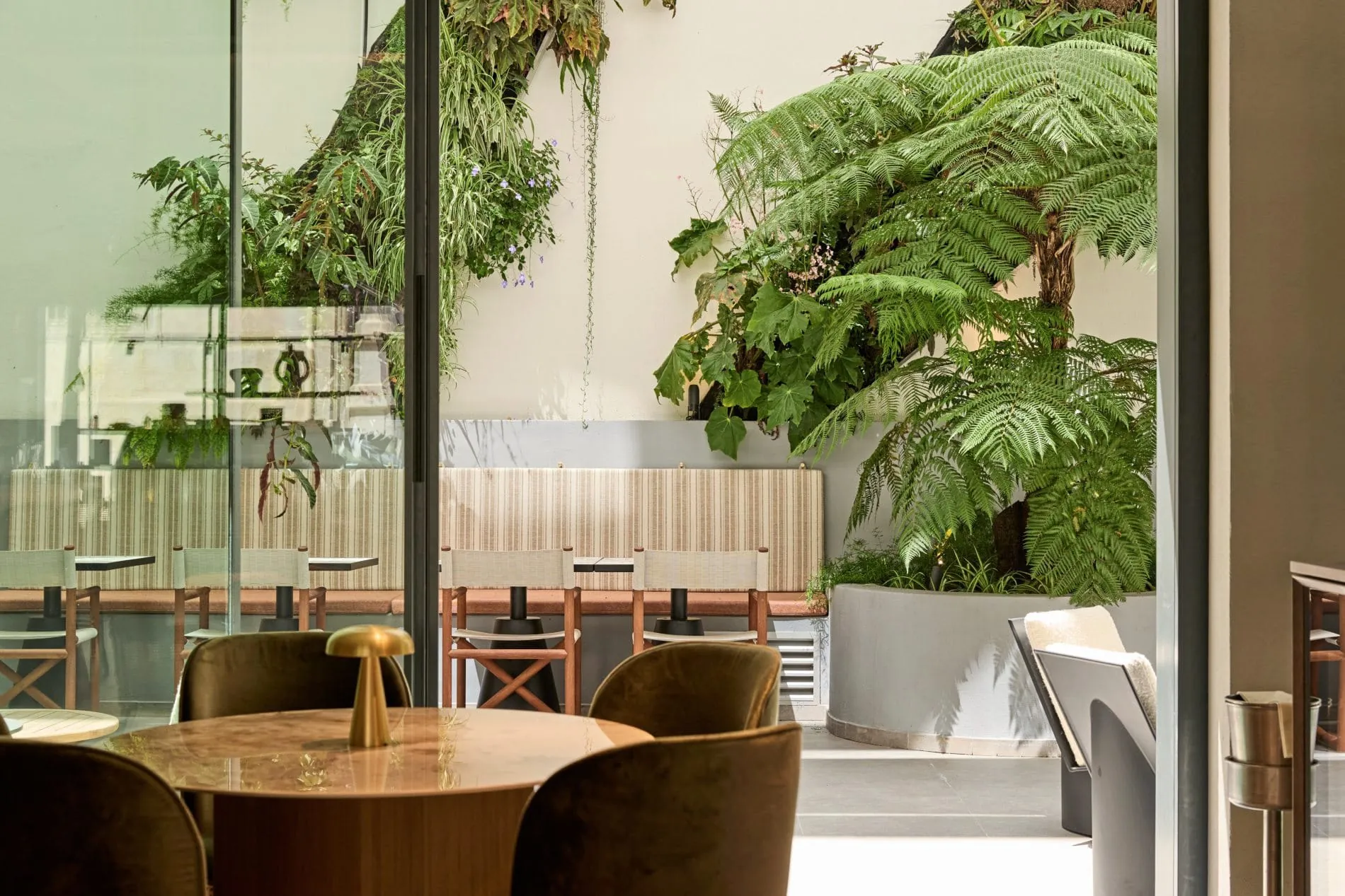 Großflächige Glasflächen verbinden die Lounge mit dem üppig bepflanzten Innenhof.