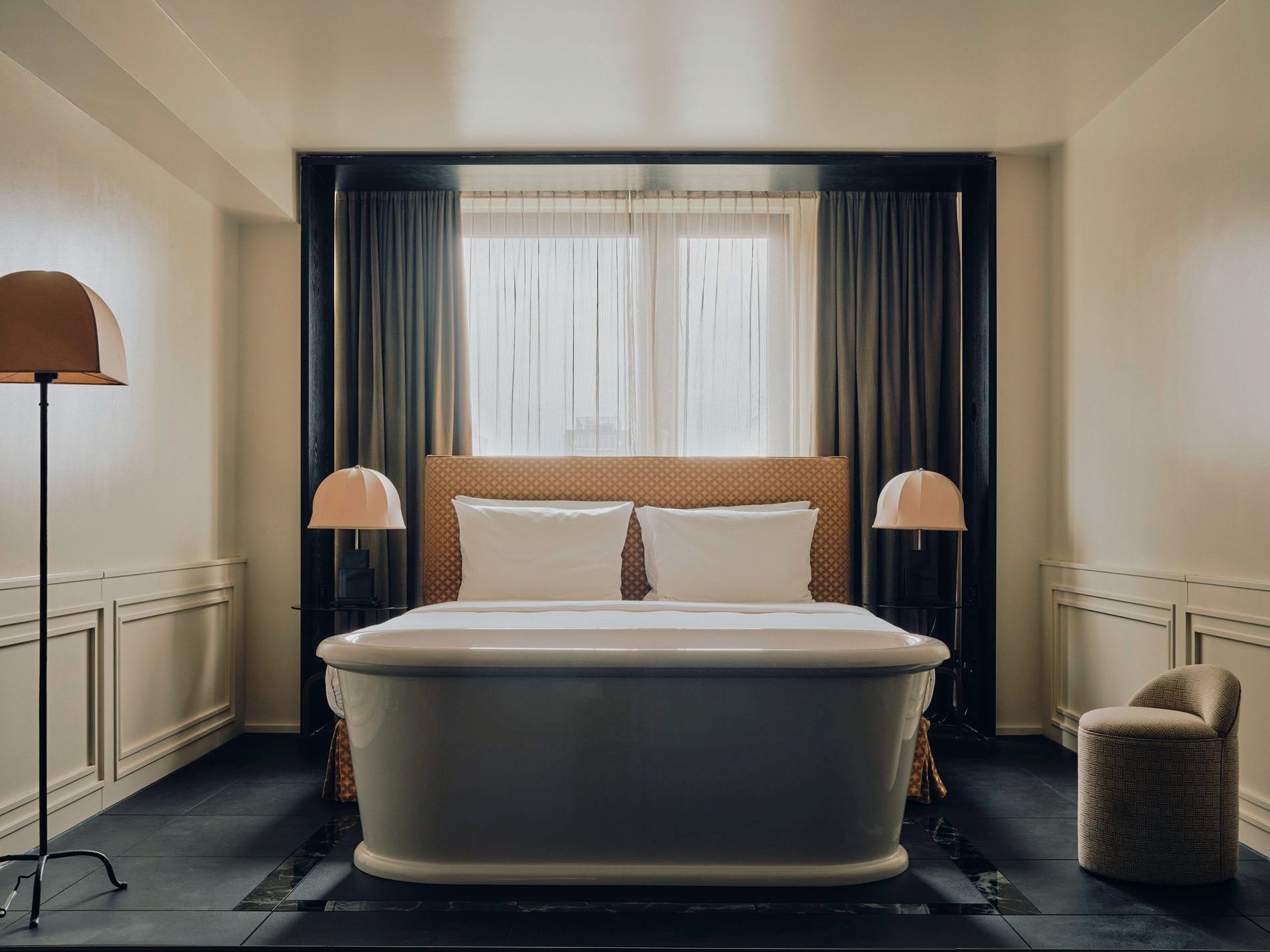 Ein besonderes Highlight der Junior Suite ist die freistehende Badewanne, die offen im Raum direkt vor dem Doppelbett platziert ist.