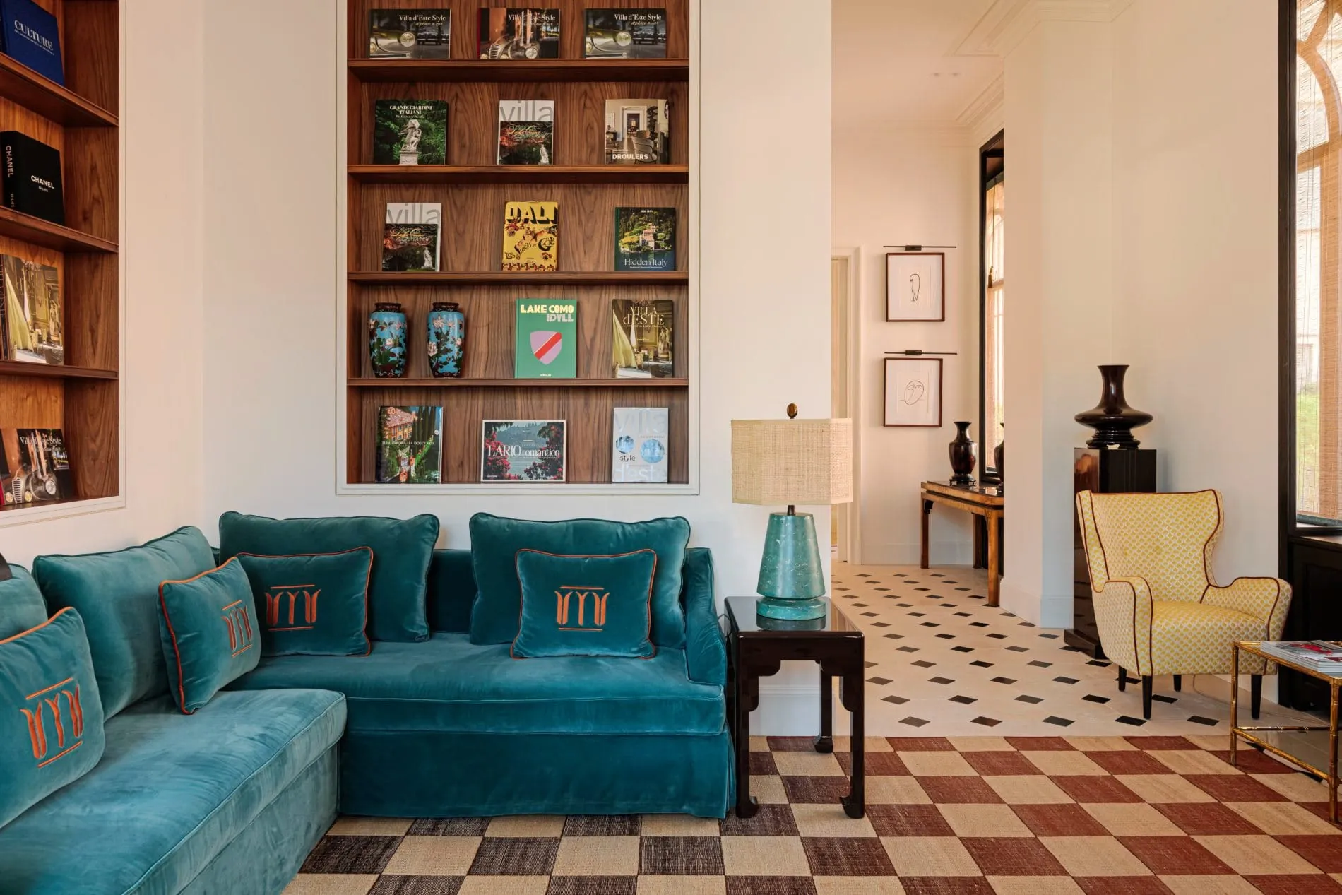 Der Salon der Miralago Luxury Apartments kombiniert ein elegantes Samtsofa in Petrol mit maßgeschneiderten Designelementen, die vom Studio Droulers entworfen wurden.