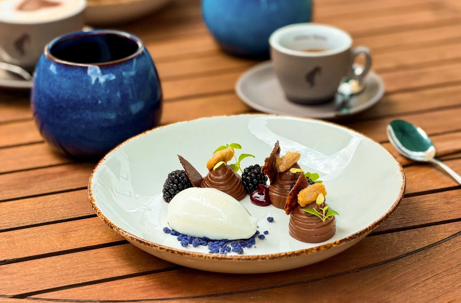 Aus dem aktuellen Saison-Menü der Elbuferei: Dessert aus Brombeere und Lavendel, kombiniert mit Schokolade, Sorbet aus alkoholfreiem Gin und Mandel, serviert mit hausgemachtem Eistee.
