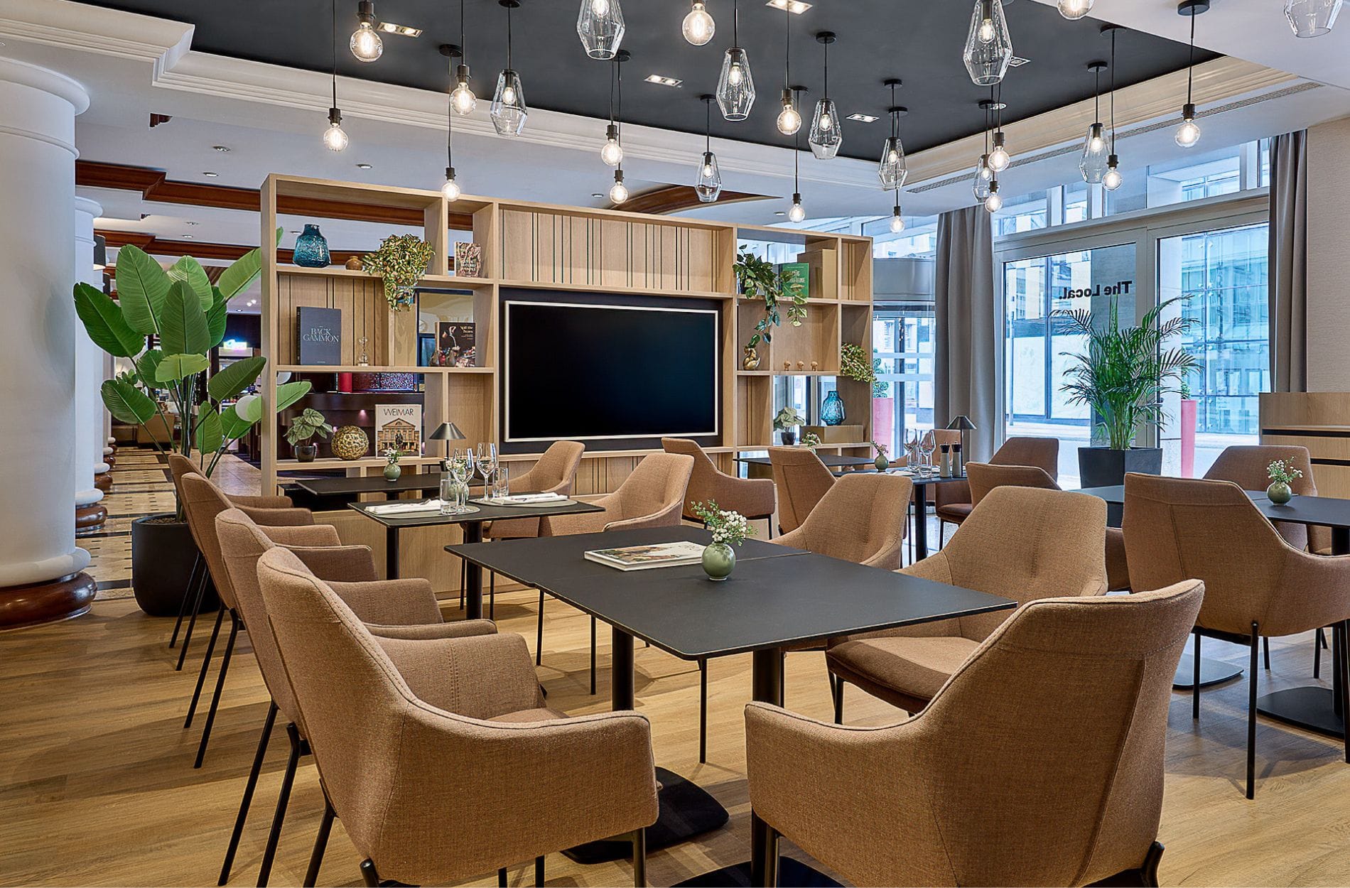 Das wiedereröffnete Restaurant The Local im Leipzig Marriott setzt auf ein modernes Interieur mit hellem Holz, schwarzem Metall und gedeckten Blau-, Braun- und Beigetönen. Unterschiedliche Sitzbereich und ein Bartresen sollen Hotel- und externe Gäste gleichermaßen ansprechen.