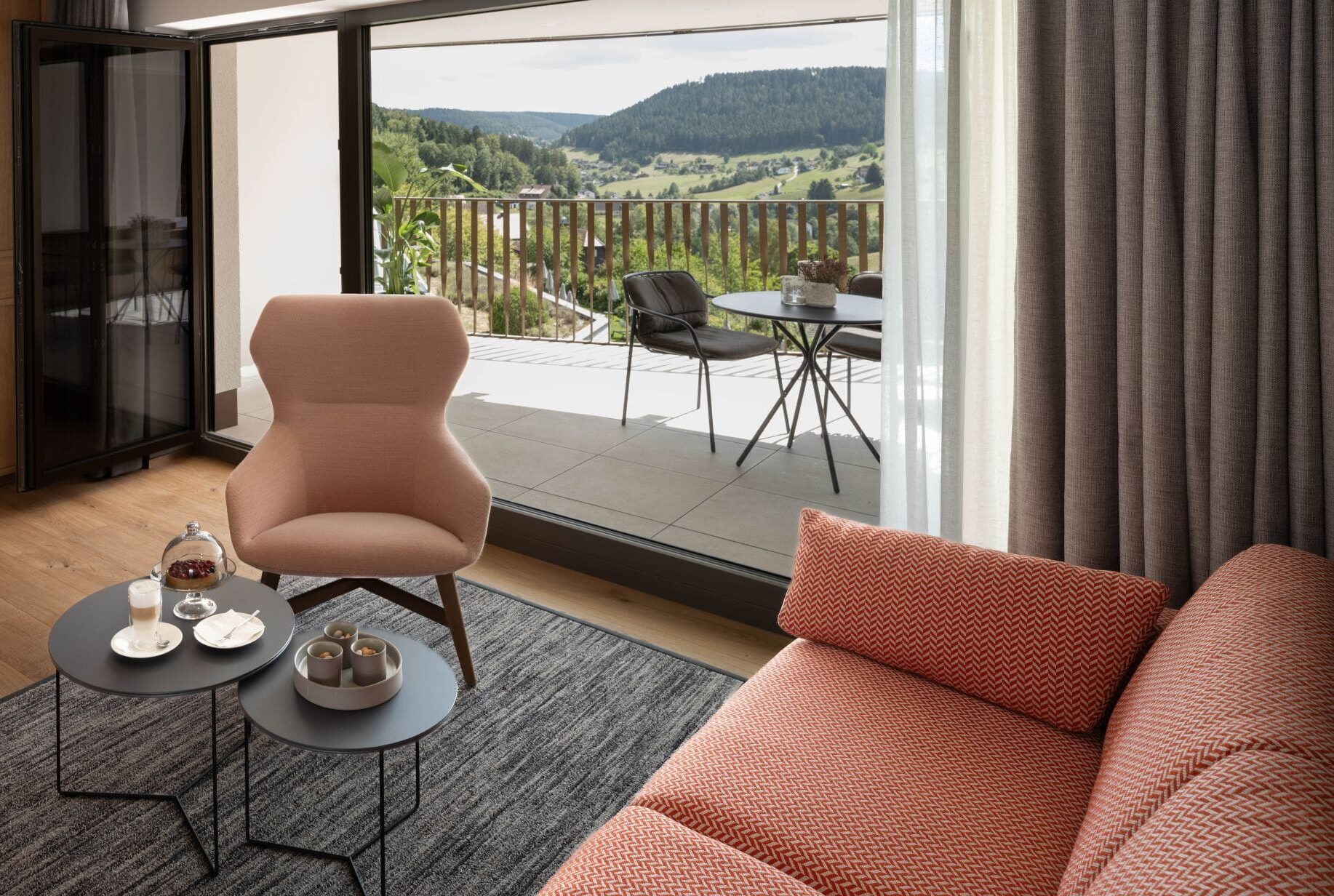 Mehr Raum für den Urlaub: Warme Hölzer und hochwertige Textilien machen den Sitzbereich der neuen Suite zum Wohn­zimmer. Bodentiefe Fenster öffnen den Blick auf den Balkon und ins grüne Tonbachtal.