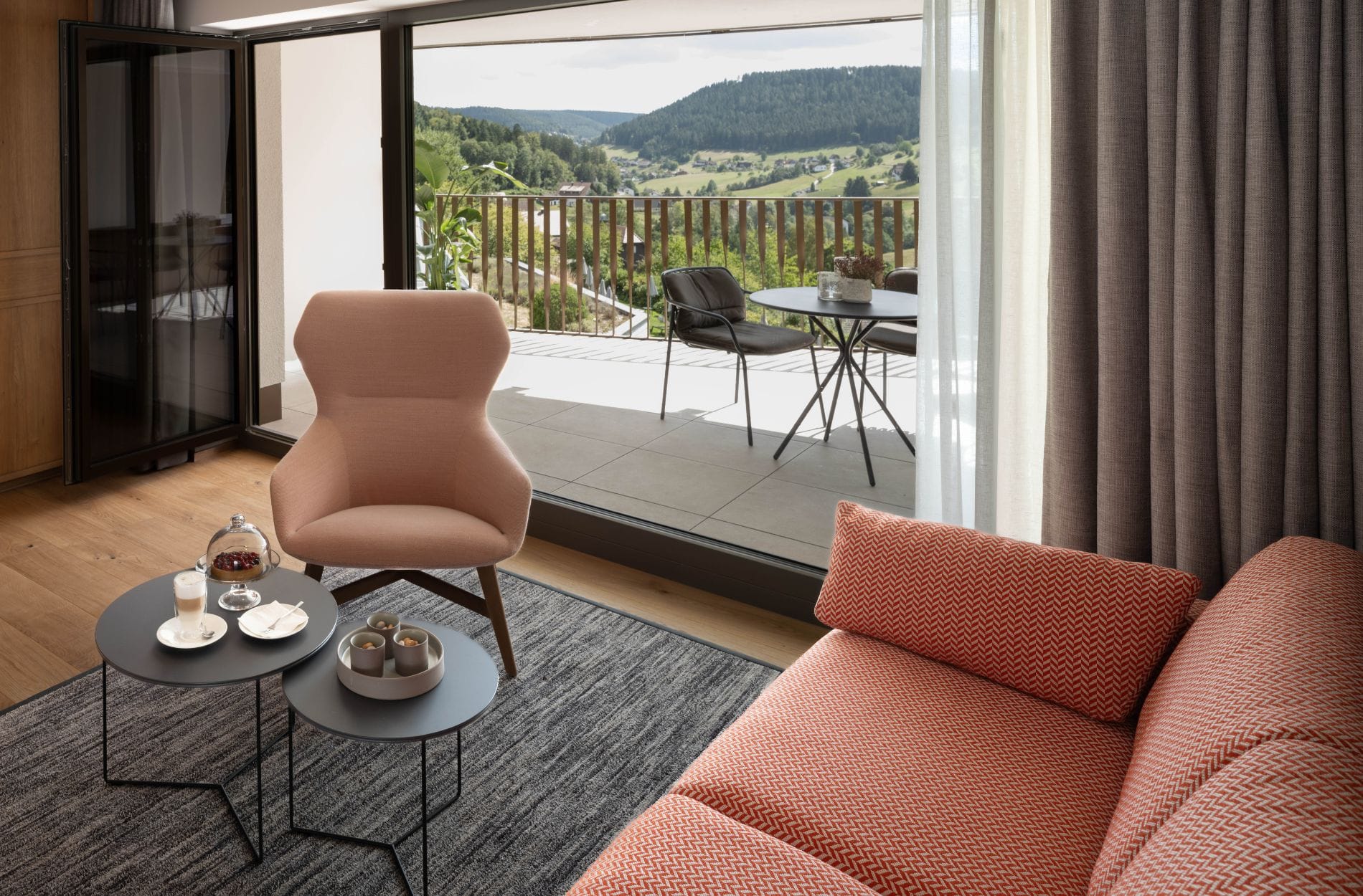 Mehr Raum für den Urlaub: Warme Hölzer und hochwertige Textilien machen den Sitzbereich der neuen Suite zum Wohn­zimmer. Bodentiefe Fenster öffnen den Blick auf den Balkon und ins grüne Tonbachtal.