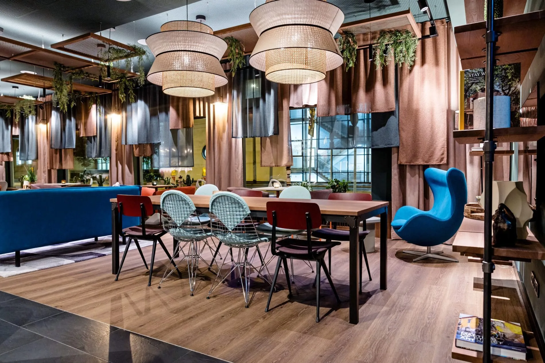 Das Interior kombiniert industrielle Anklänge mit warmen Materialien und kräftigen Farben. Blau, Türkis, Orange und Rostrot ziehen sich als wiederkehrende Akzente durch die öffentlichen Bereiche.