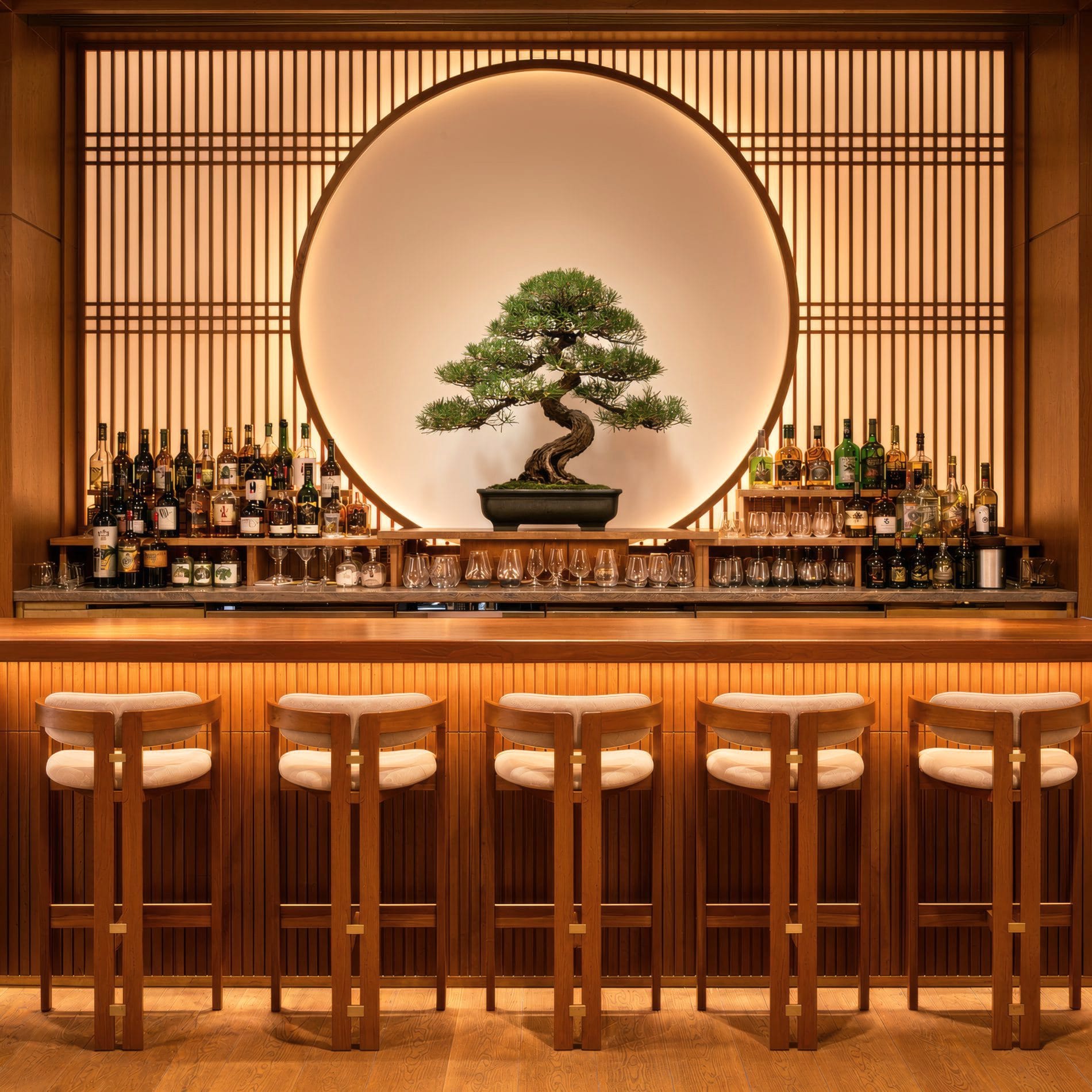 Die Hotelbar ist ein zentraler Treffpunkt für Begegnungen und spiegelt japanisch inspirierte Designkonzept wider. Ein beleuchteter Bonsai-Baum im Zentrum der Rückwand setzt einen stilvollen Akzent.