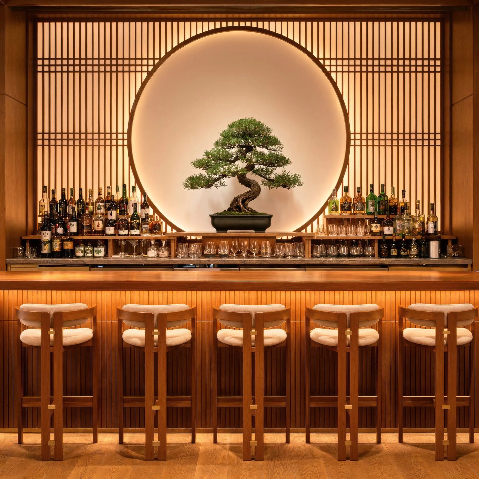 Die Hotelbar ist ein zentraler Treffpunkt für Begegnungen und spiegelt japanisch inspirierte Designkonzept wider. Ein beleuchteter Bonsai-Baum im Zentrum der Rückwand setzt einen stilvollen Akzent.