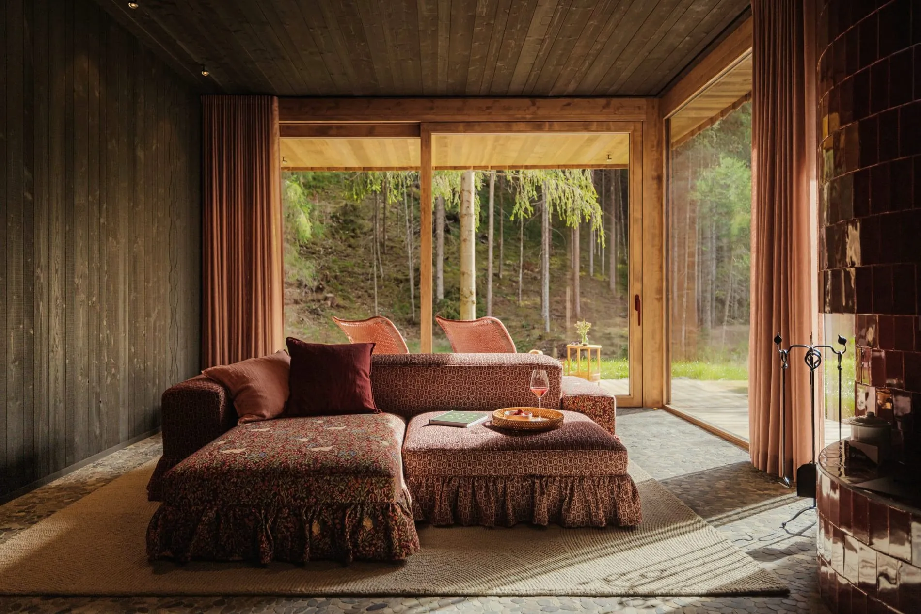 Das von Atelier Zürich gestaltete Interior verbindet traditionelle Tiroler Materialien mit hochwertigen Stoffen und bietet durch bodentiefe Fenster einen direkten Blick in den angrenzenden Wald.